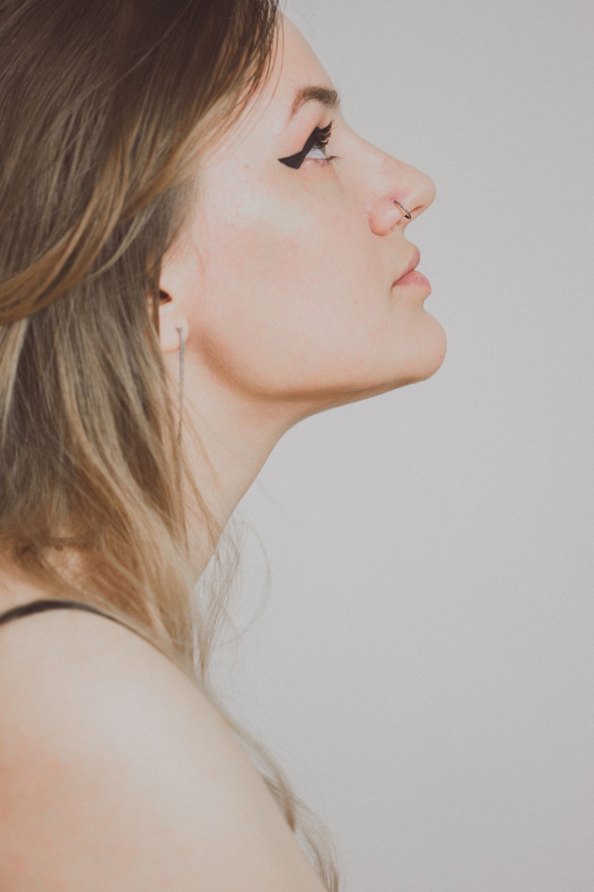 Side profile portrait of a young woman, the profile view rhinoplasty patients study most before choosing a surgeon