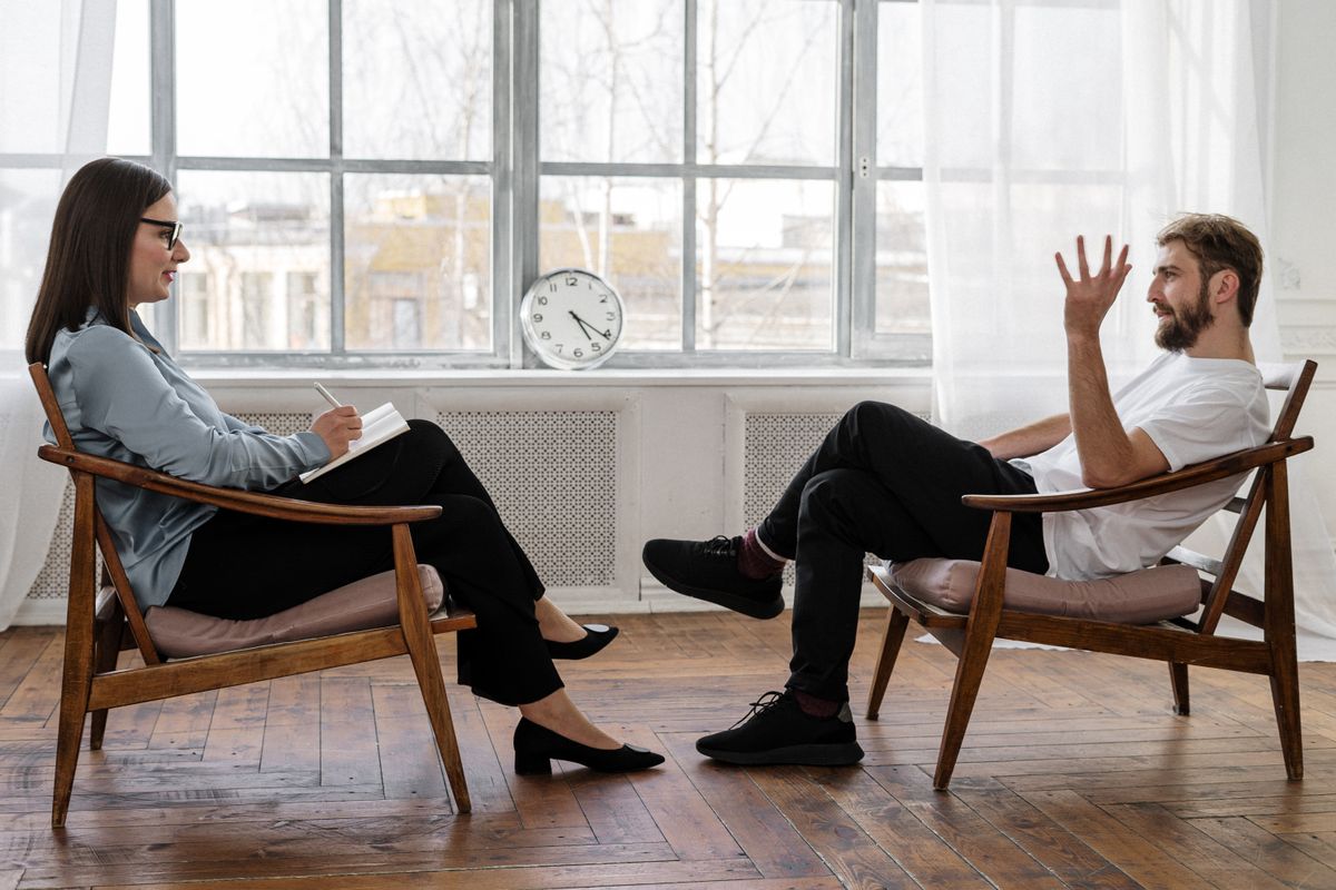 A therapist and client talking in a calm counseling session, the moment a mental health practice works to earn