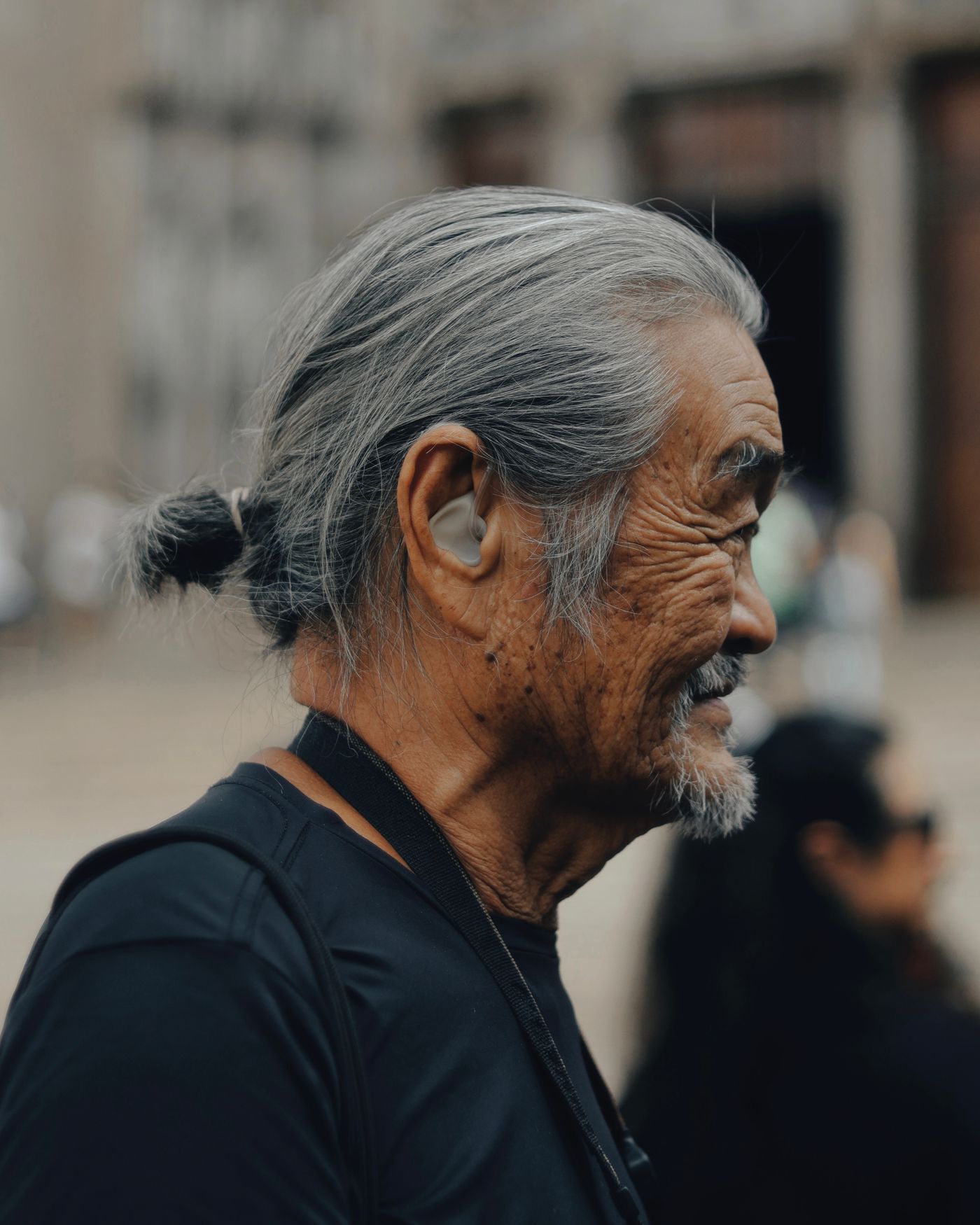 A smiling senior man wearing a hearing aid outdoors, representing a patient who finally got hearing care from an audiology practice