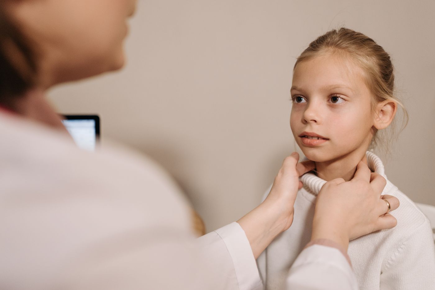 A physician examining a patient's neck and thyroid, representing an endocrinology practice that treats thyroid, diabetes and hormone conditions