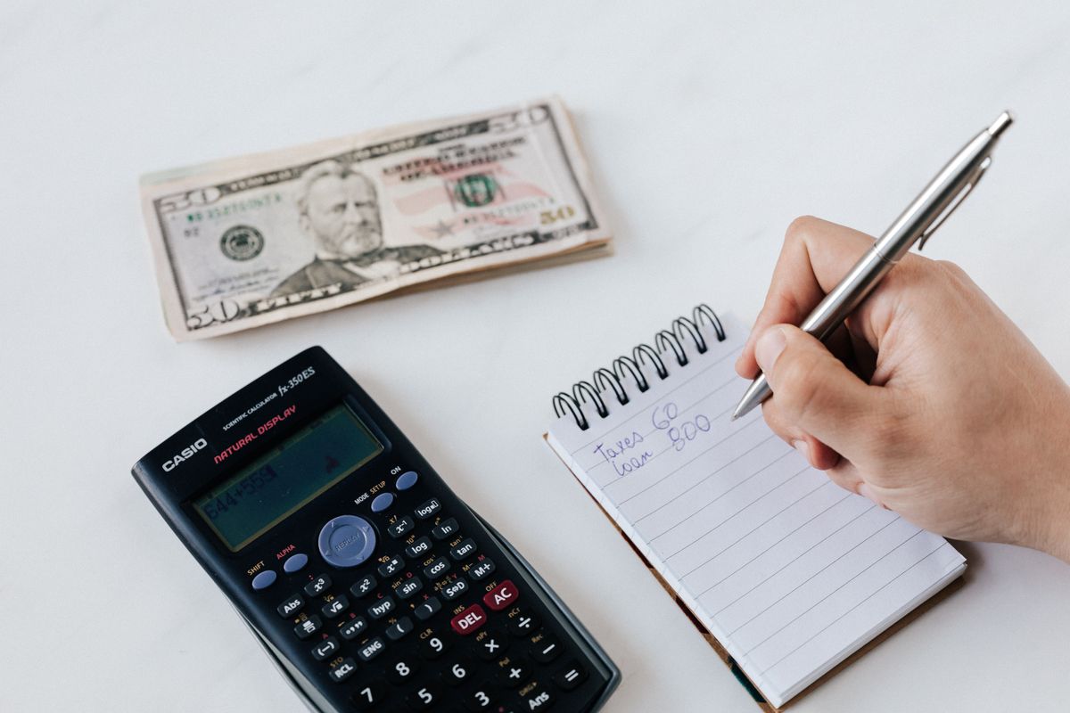 Calculator, cash and a notepad on a desk, representing how a medical practice sets and presents its prices to patients