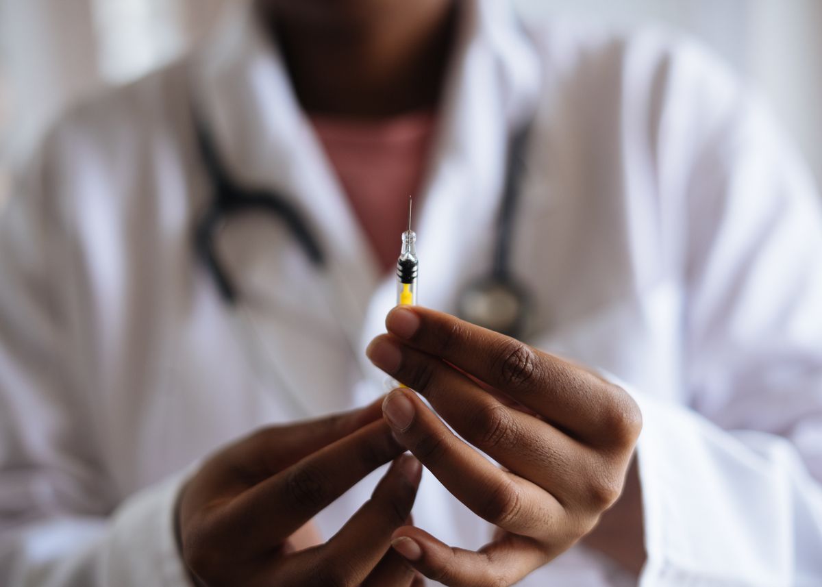 A doctor in a white coat holding a syringe, representing a medical practice launching a new treatment or service line such as injectables or weight management