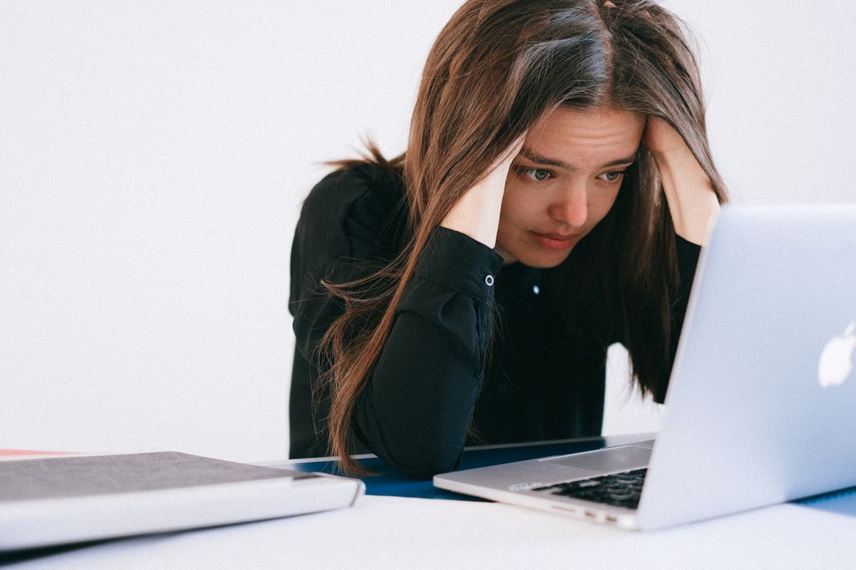 A medical practice owner looking stressed at a laptop after finding a fake Google review on the practice profile