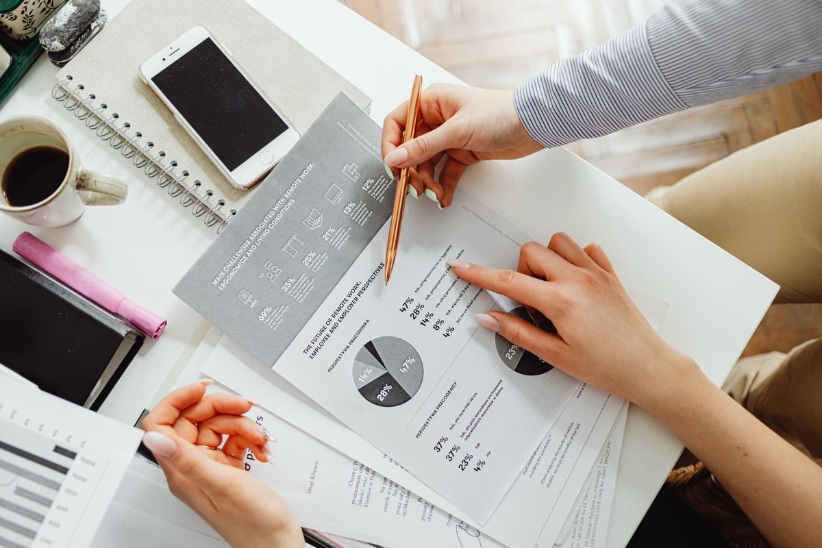 Two people reviewing marketing charts and data on a desk, doing competitor research for a medical practice