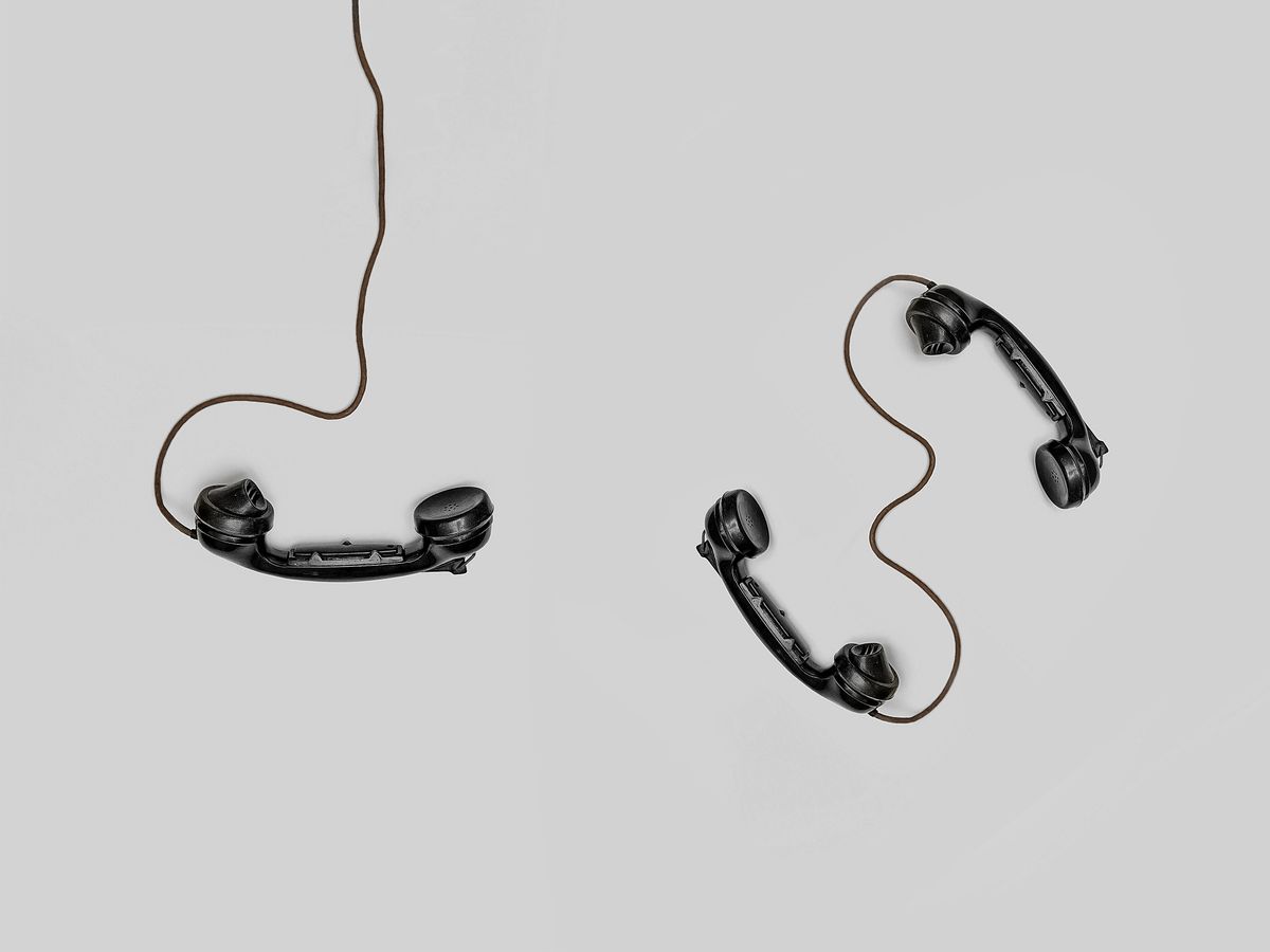 Two disconnected phone handsets on a gray background, a picture of phone tag between a medical practice and its patients