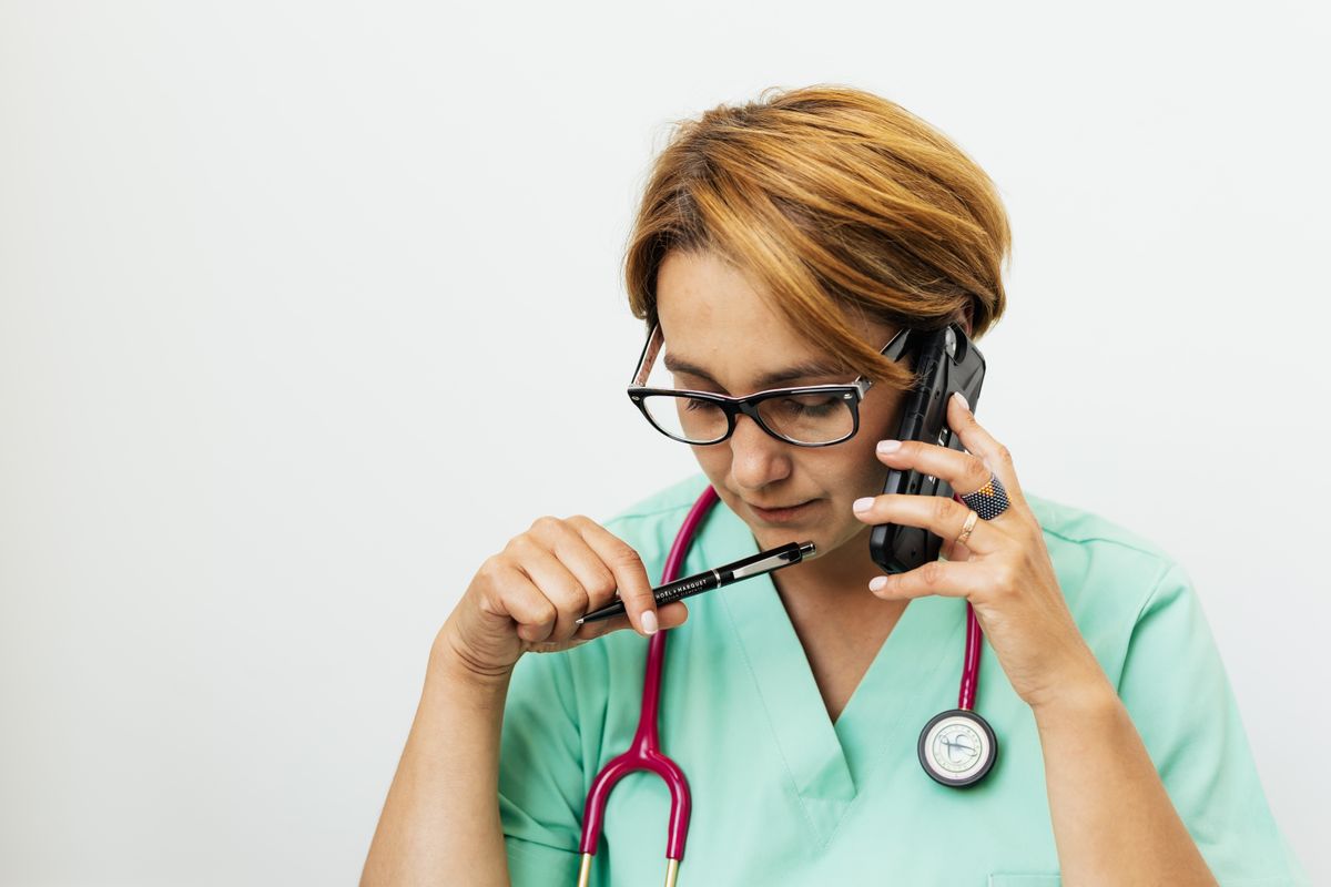 A medical professional on the phone checking a patient's insurance, the everyday friction that keeps new patients from booking