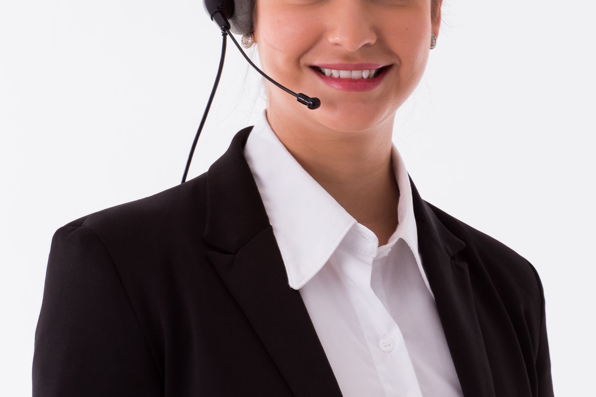 A smiling call center agent wearing a headset, representing a medical answering service answering patient phone calls