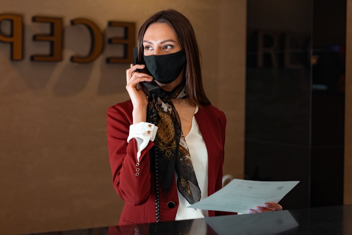 A medical receptionist answering a phone call at the front desk of a practice