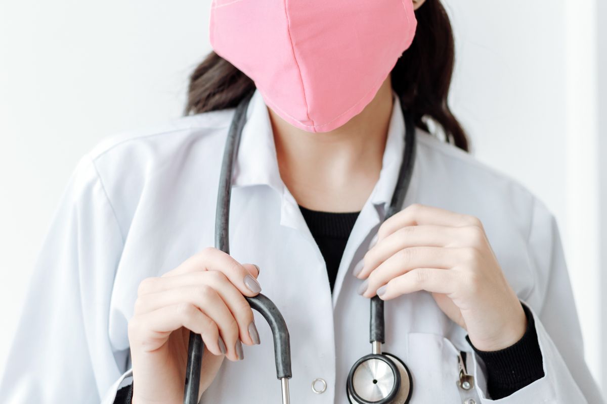 A doctor at a laptop reviewing an online profile and patient reviews, weighing whether Healthgrades is worth it for a medical practice