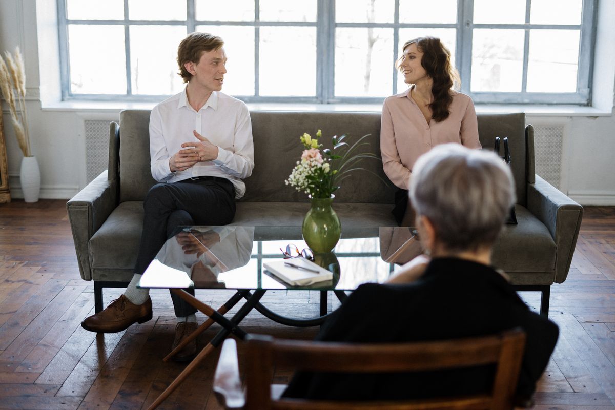 Two people talking warmly in a bright room while a third listens, the everyday word of mouth conversation that sends patients to a medical practice