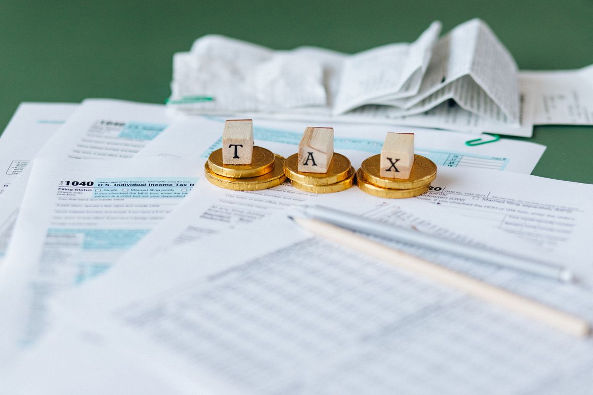 Calculator, tax forms and a pen on a desk representing a medical practice deducting its marketing expenses