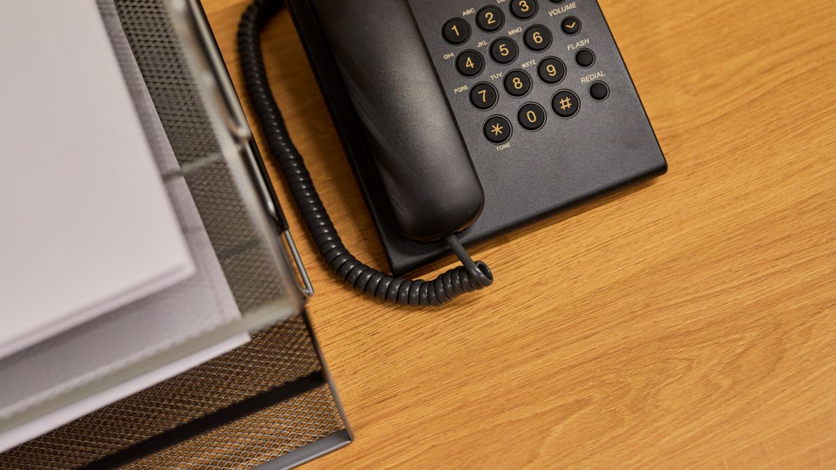 A front desk phone sitting on an empty reception desk, the moment a patient calls at lunch and no one is there to answer