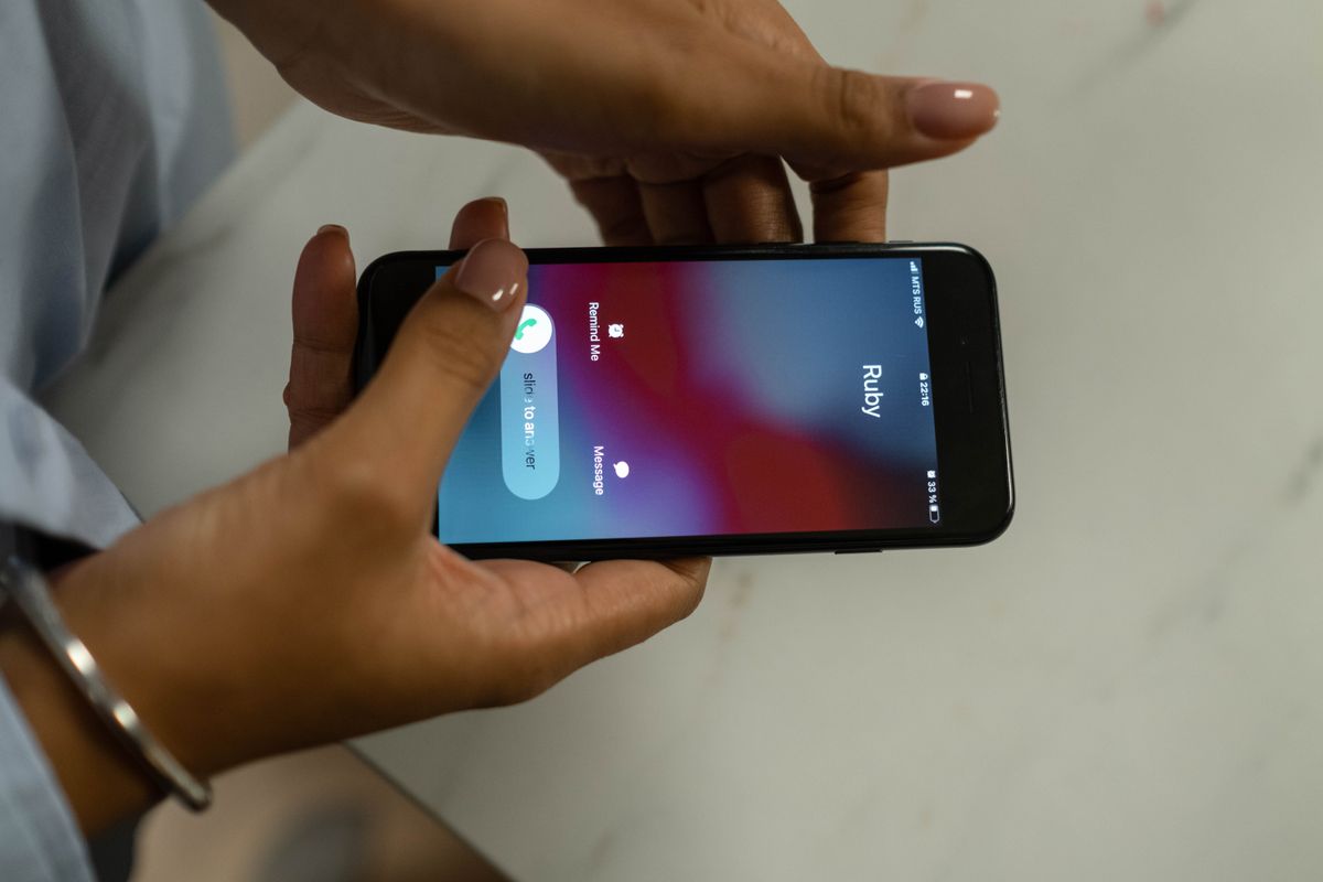 Patient holding a smartphone with an incoming call, deciding whether to answer a number that could be flagged as spam
