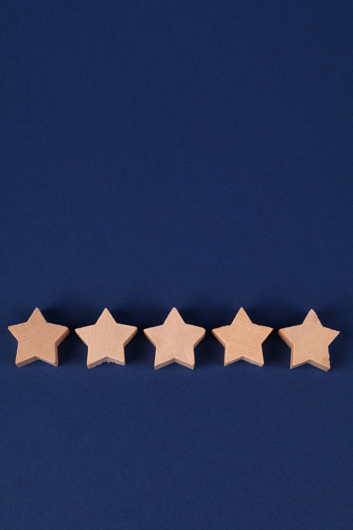 Five wooden review stars on a deep blue background, representing Google reviews for a medical practice