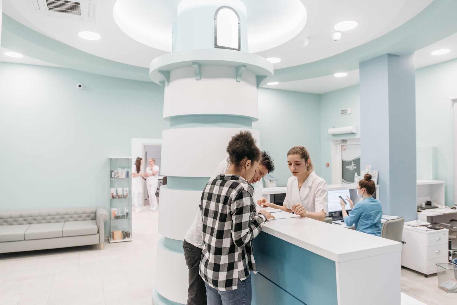 A patient and a companion registering at a clinic reception desk before a first appointment