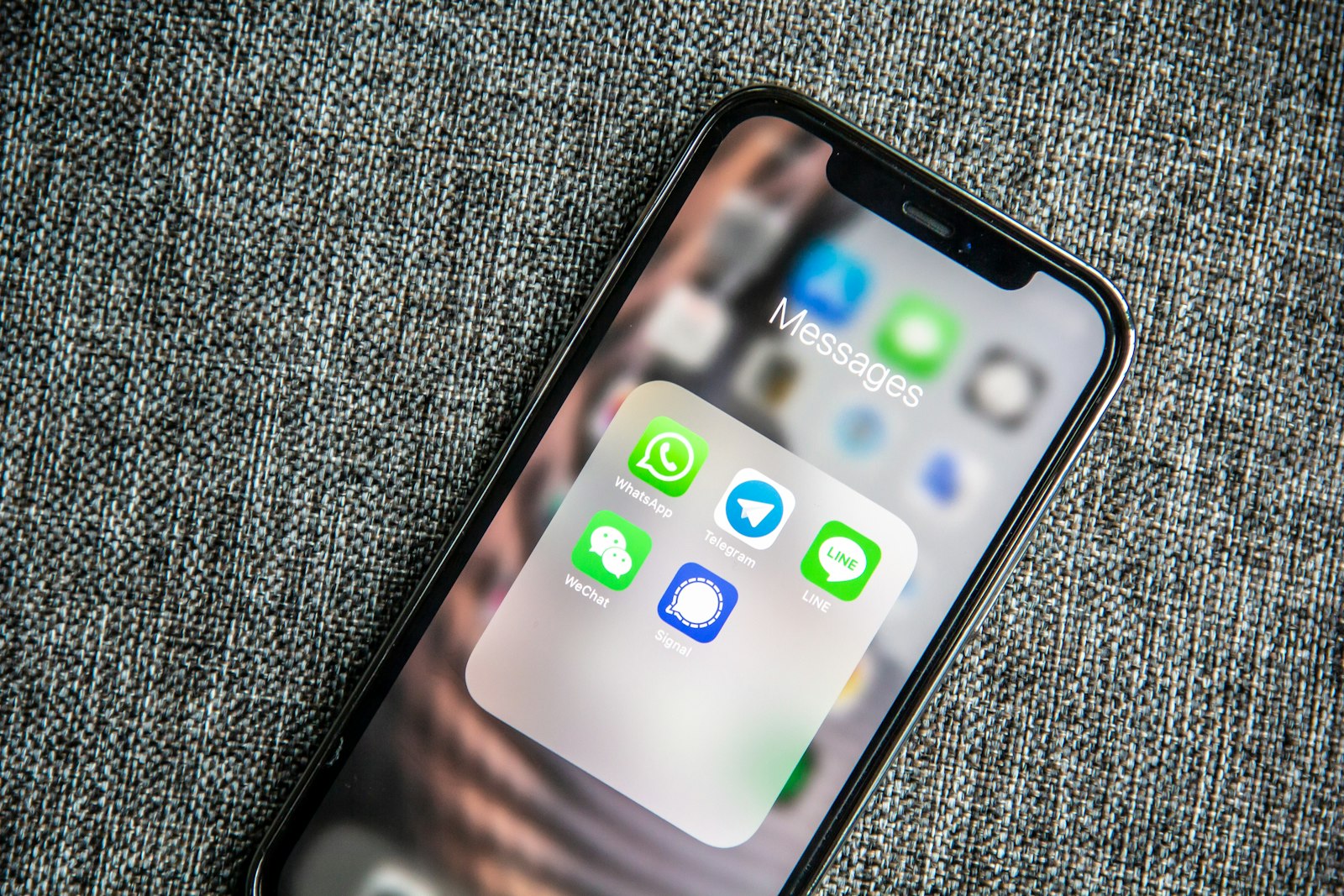 A smartphone showing a folder of messaging apps, the channel where patient communication AI now lives for a medical practice