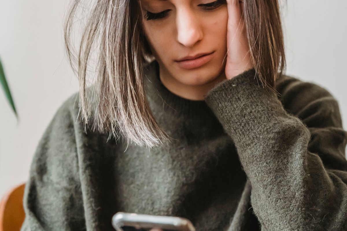 Person reading a worrying patient complaint on a smartphone, a common moment for medical practice owners