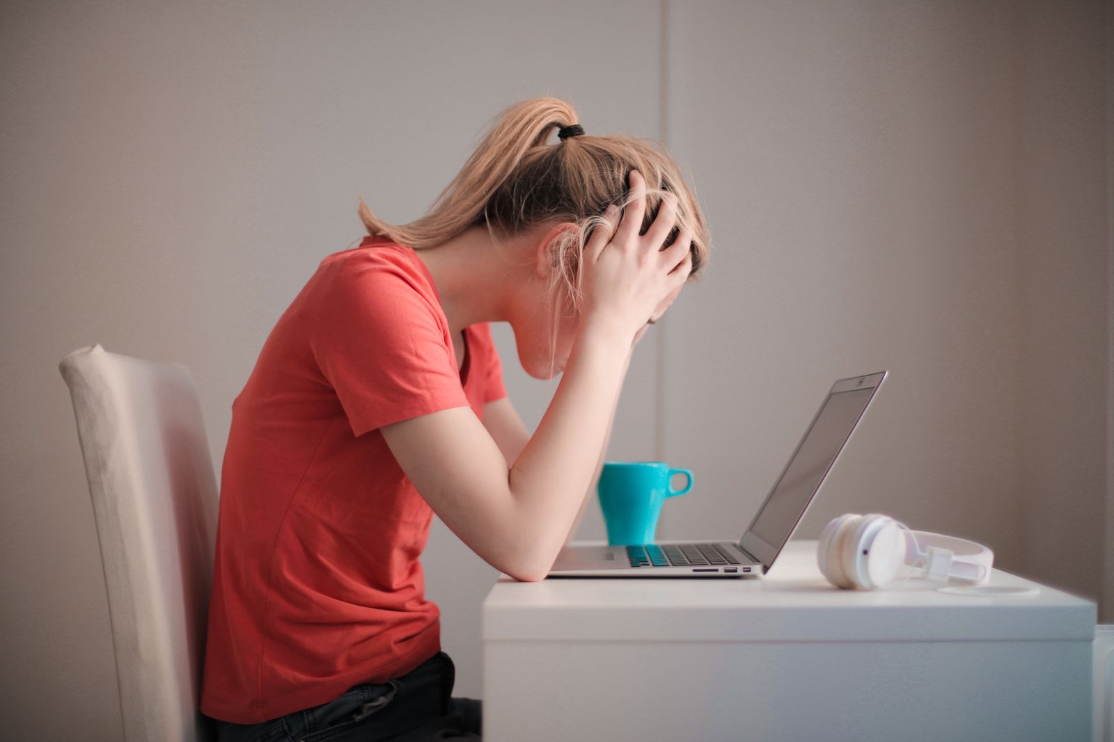 Frustrated patient with head in hands at a laptop while trying to book a medical appointment online