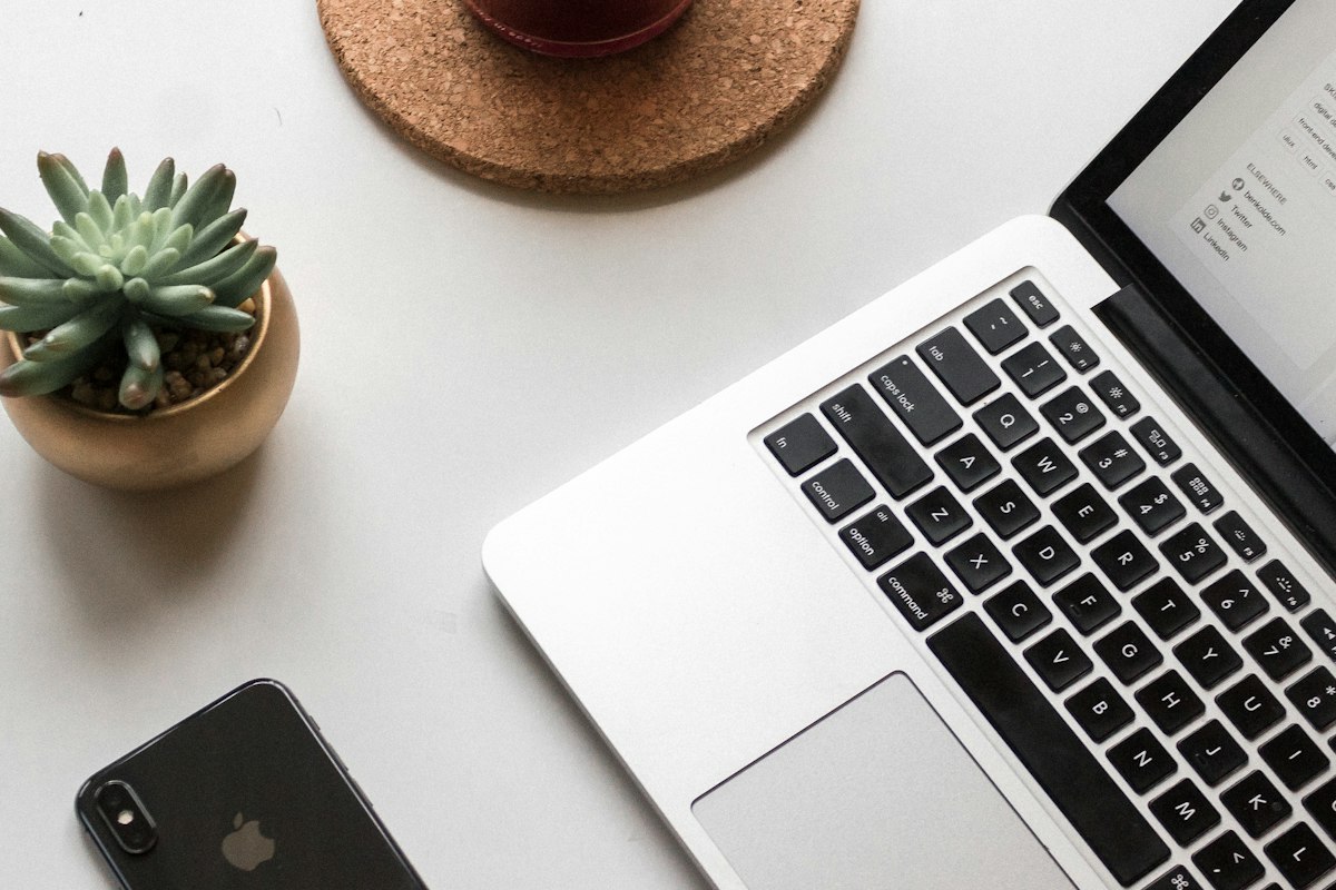 A laptop and phone on a desk, the way a patient searches for a new doctor through AI and then lands on a practice website to book