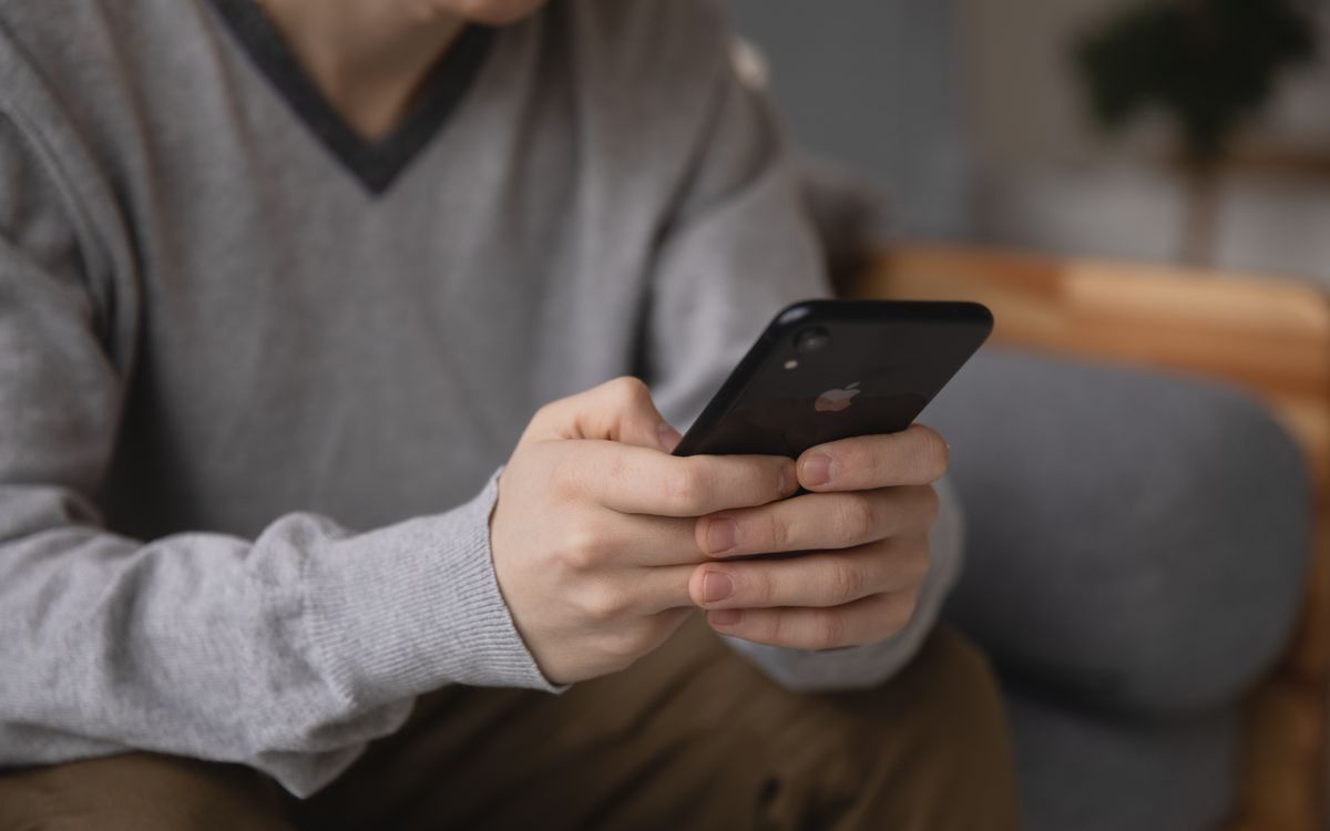 A patient at home on the couch using a phone to check AI about their diagnosis after a doctor visit