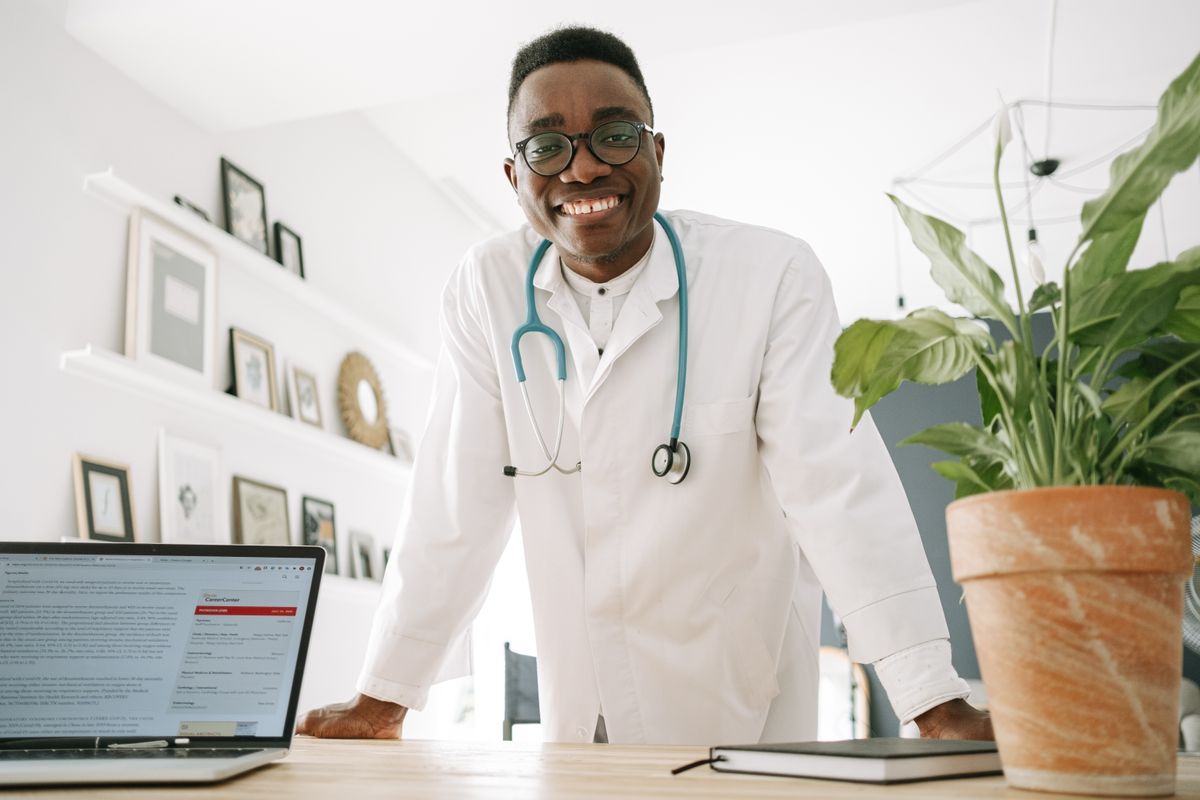 A doctor in a white coat smiling in a modern office, representing a trustworthy personal brand for a medical practice