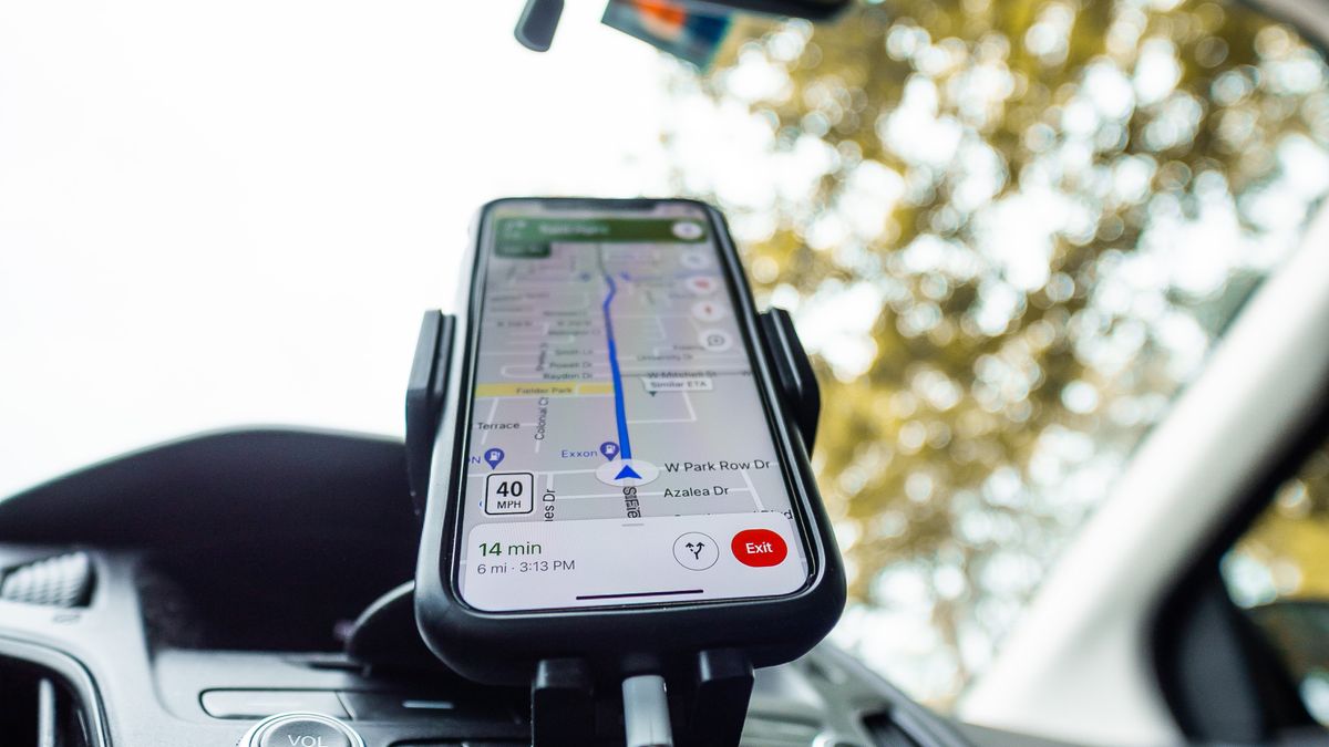 A smartphone mounted on a car dashboard running a GPS navigation app, the way a patient drives to a medical practice