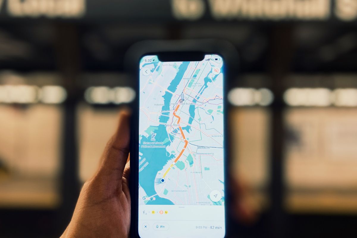 Patient holding a phone with a map open, searching for a medical practice in a nearby town, the moment a local landing page decides whether you show up