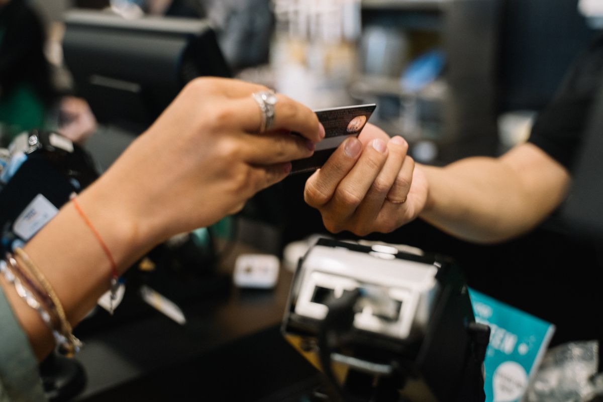 A patient handing a credit card to staff at a front desk counter, the moment many practices now use to set up a card on file