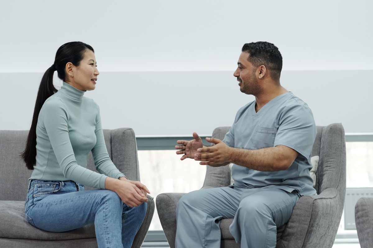 A doctor talking with a patient during a consultation, the visit that decides whether a curious lead becomes a booked patient