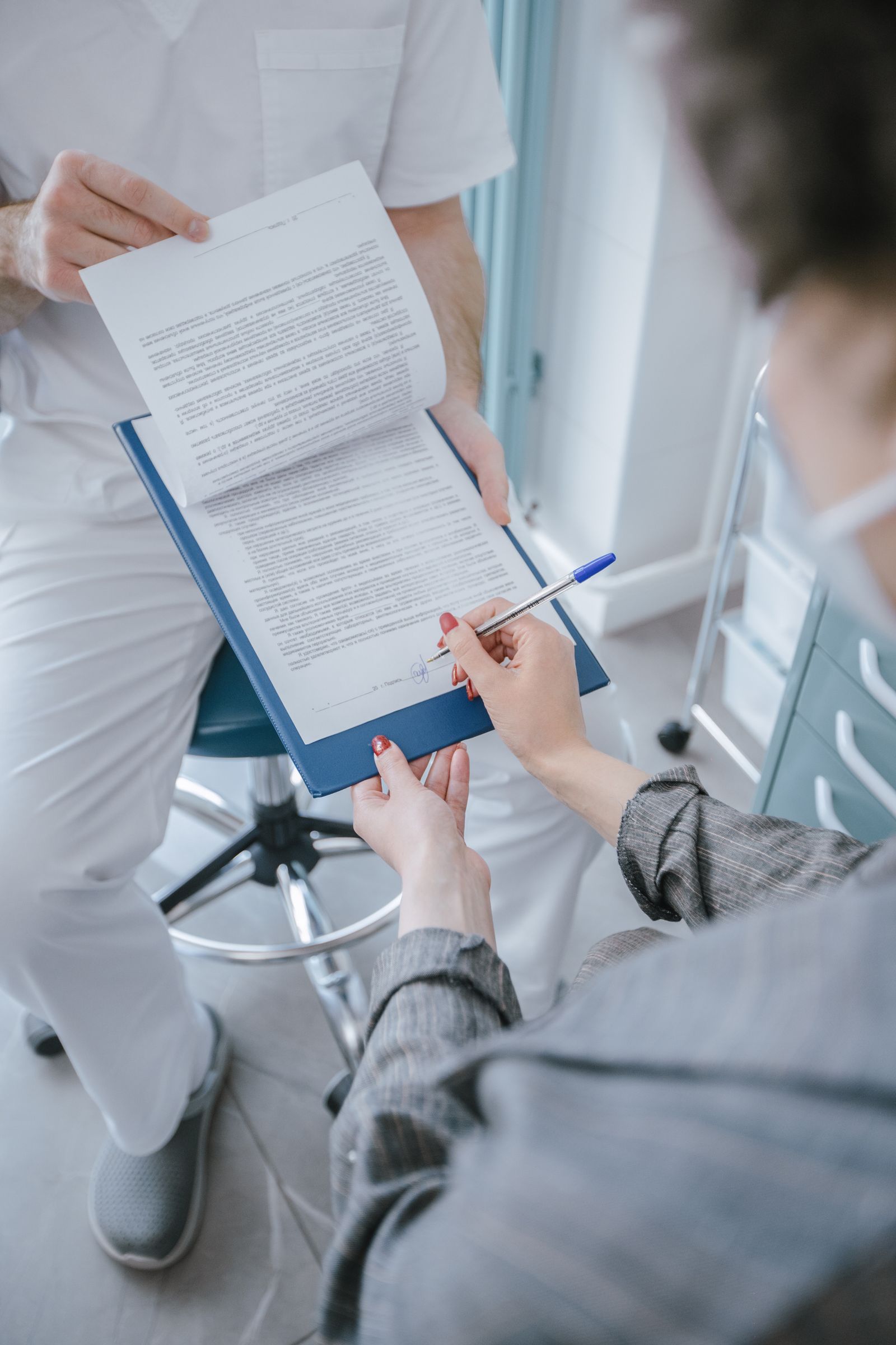 A patient reviewing and signing a consent and policy form at a medical practice before a treatment