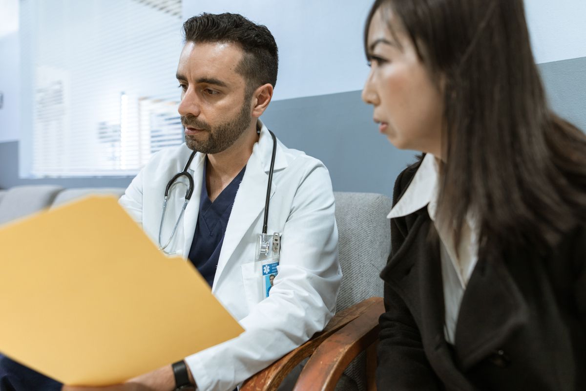 A doctor reviewing a treatment and cost document with a patient during a consultation, the moment patient financing decides whether they book