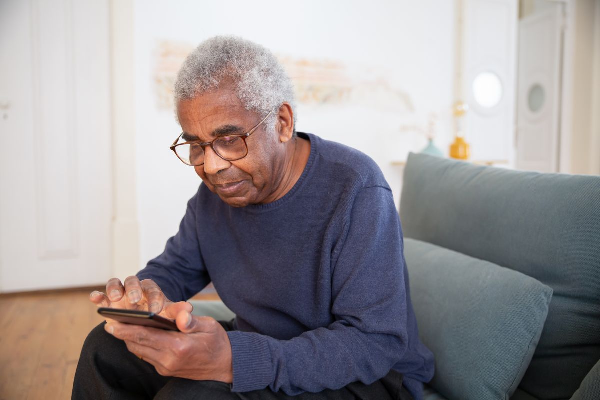 An older patient looking at his phone, about to call a medical practice to book an appointment
