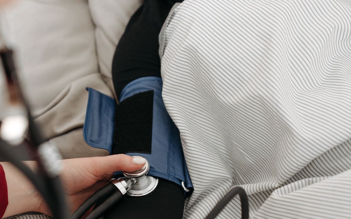 A home health provider checking a patient's blood pressure during a house call, illustrating a mobile healthcare practice that visits patients at home