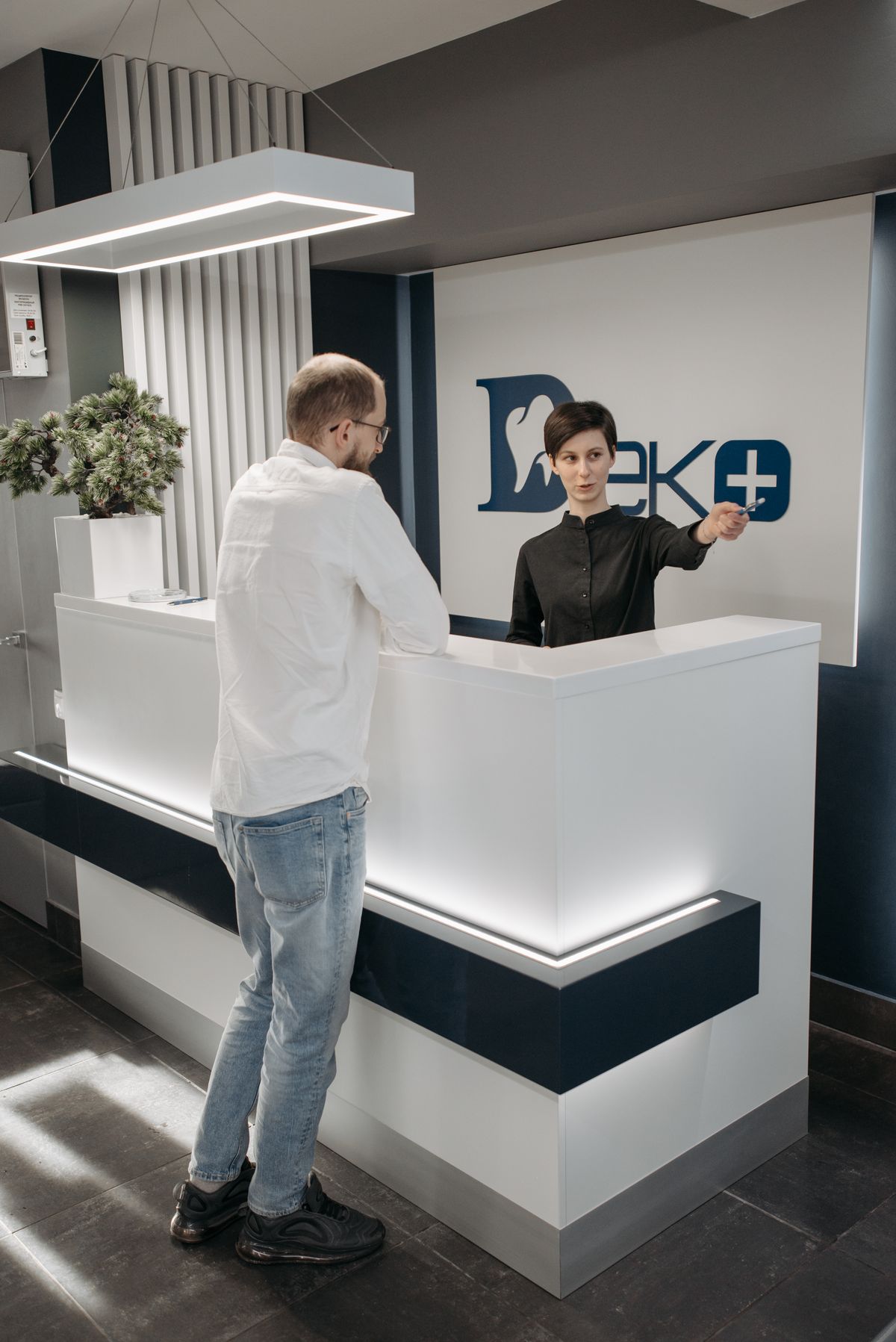 A patient at a medical practice reception desk while the front desk staff schedules the next appointment