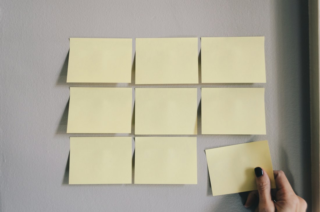 A hand removing one sticky note from a neat grid, the way a medical practice prunes weak old blog posts from its website