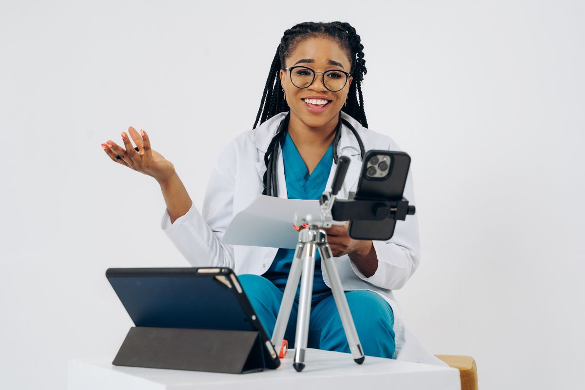 A doctor holding a smartphone and tablet, the way a practice follows up with patients after their visit