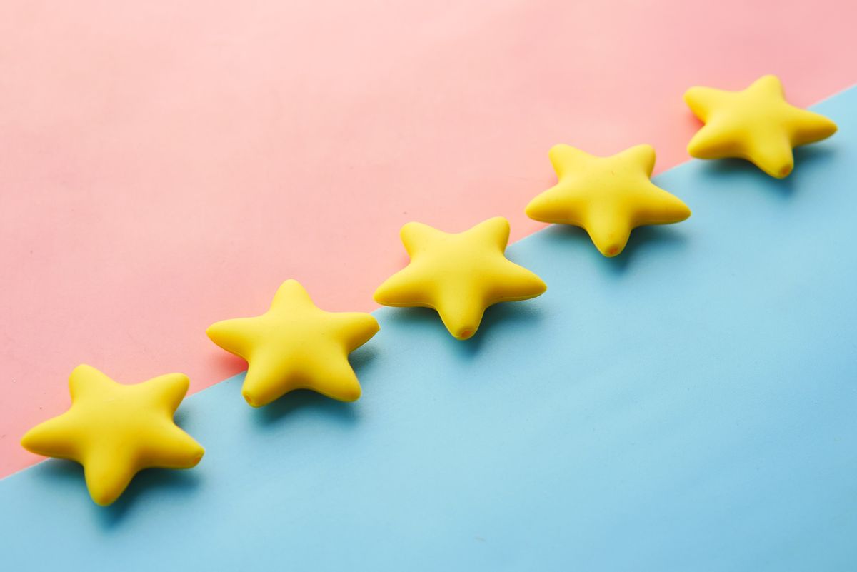 Five yellow stars lined up on a pink and blue background, representing patient reviews displayed on a medical practice website