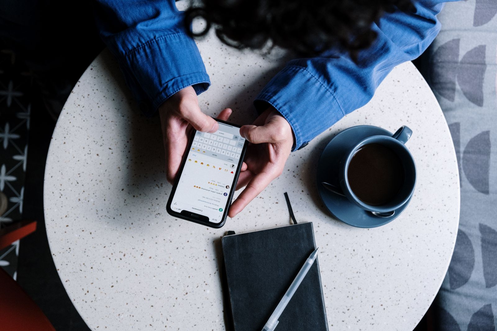 A person typing a reply on a phone over coffee, representing a medical practice responding to a positive patient review