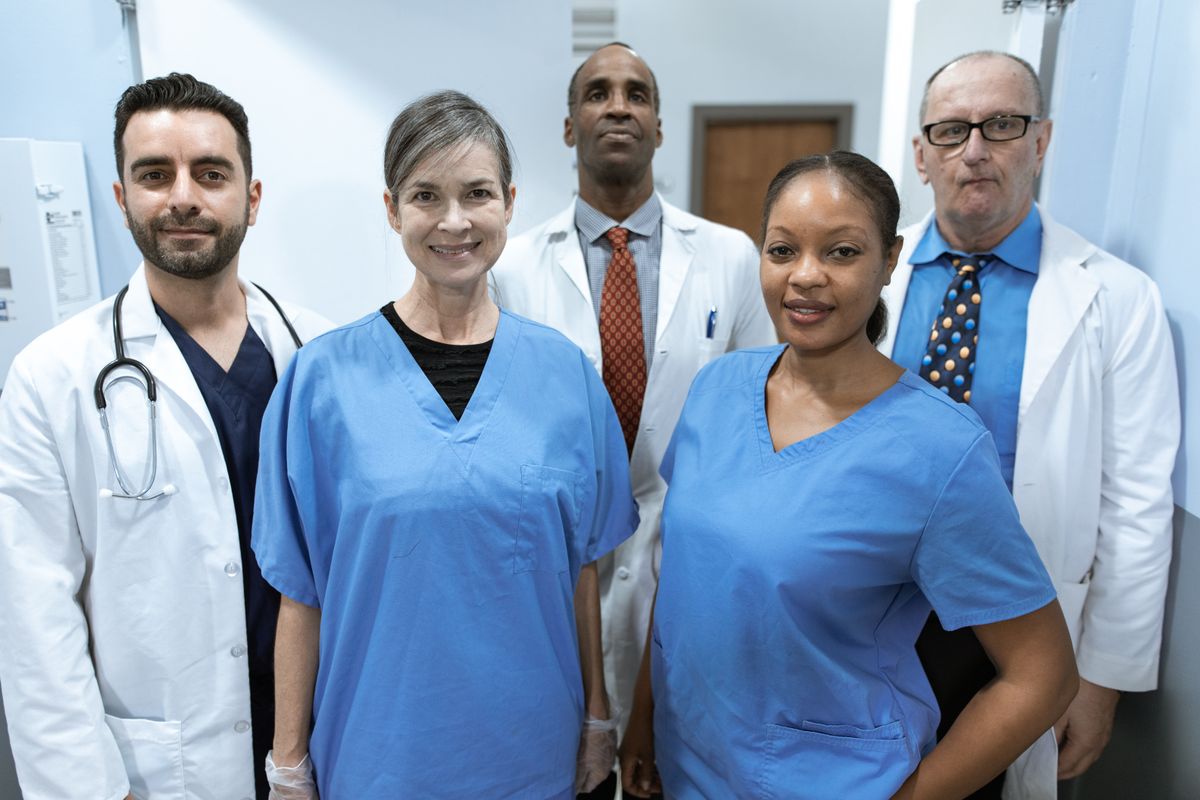 A diverse medical team of doctors and nurses smiling at the camera, the kind of real staff photo patients look for on a practice website before booking