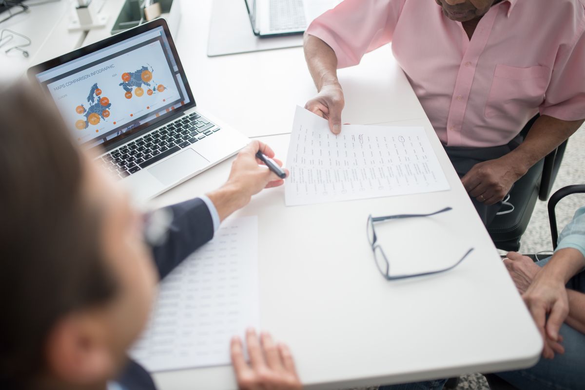 A practice owner and advisor reviewing marketing data and reports at a desk to figure out where new patients really come from