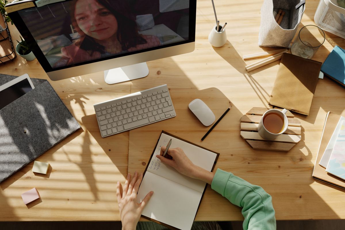 A person sits at a bright desk typing a reply on a computer, the way a practice answers Google reviews