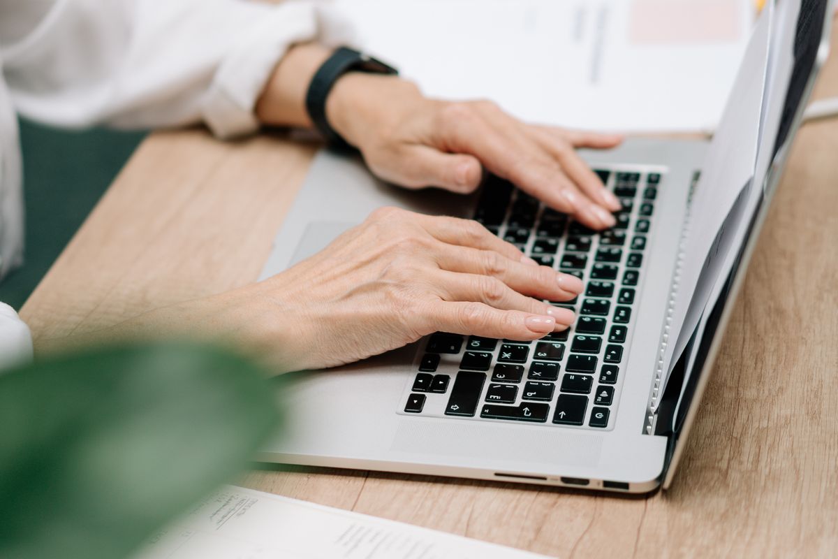 A person at a laptop typing a reply to a patient review, the daily task many medical practices are tempted to hand to AI