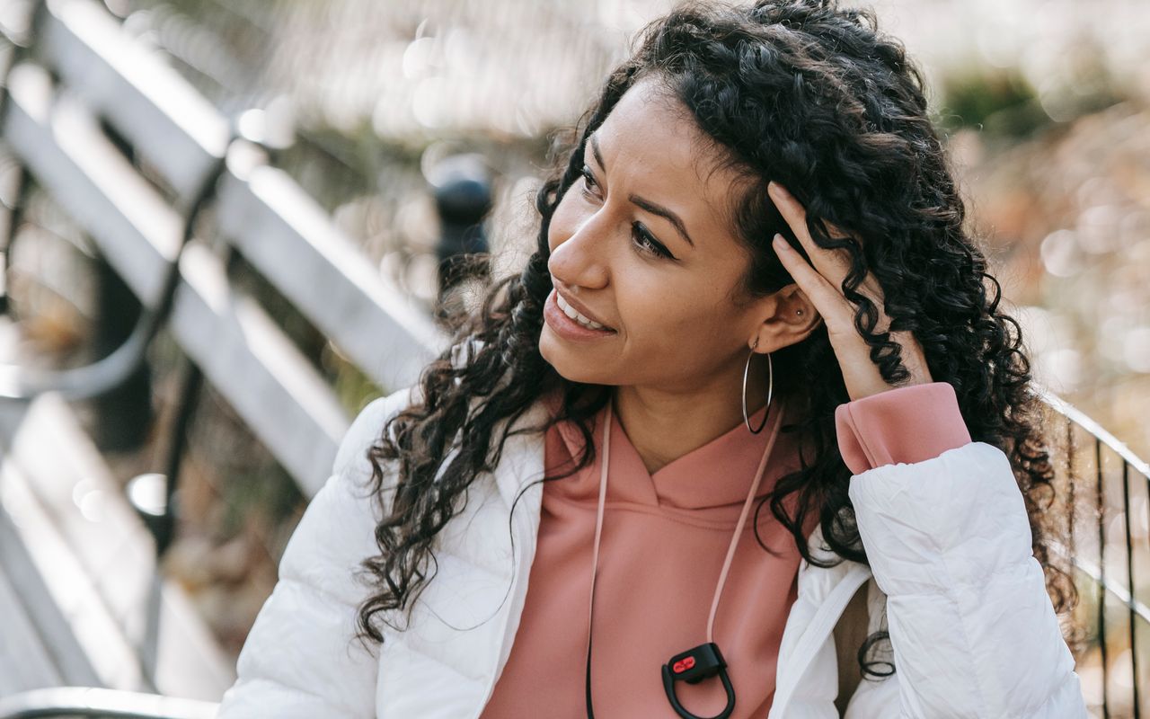 A Hispanic woman looking at her smartphone outdoors, the way most Spanish speaking patients search for and choose a medical practice