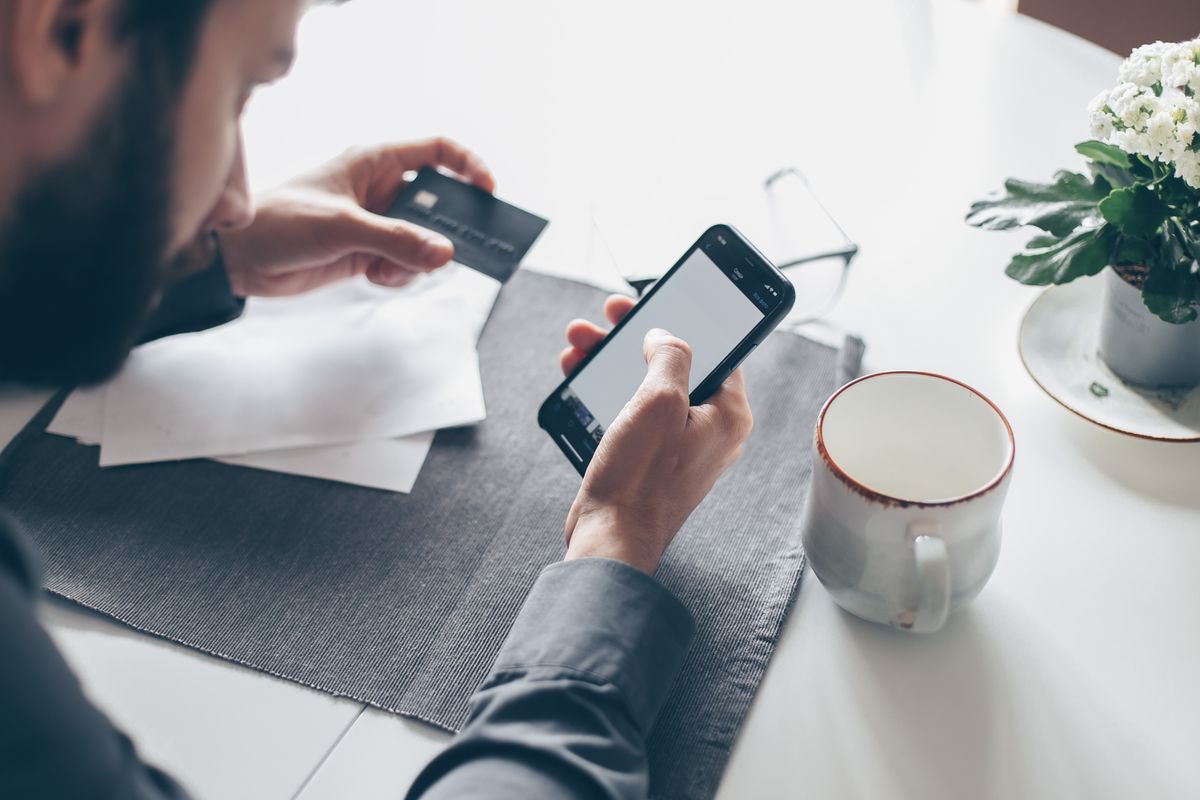 A patient holding a smartphone and a credit card, paying a medical bill from a text to pay link