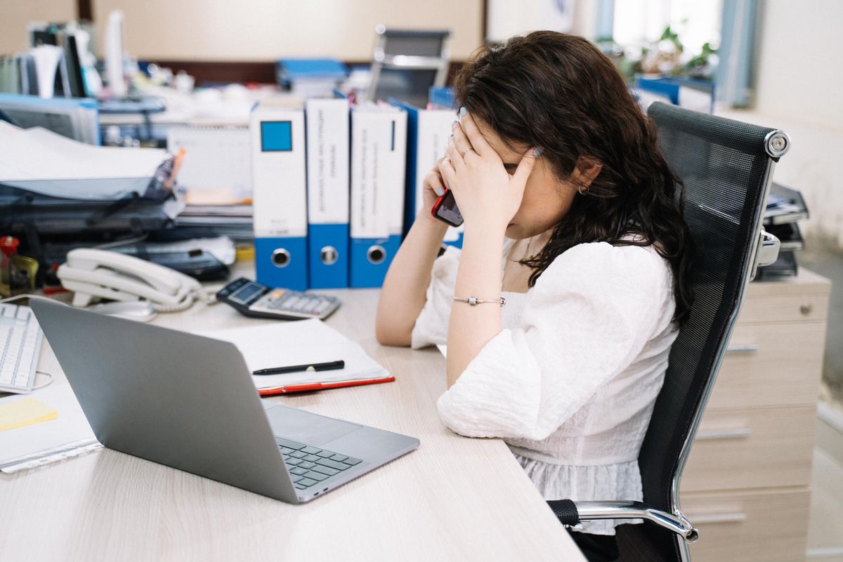 A medical practice receptionist on the phone at a busy front desk, the moment a spam call ties up the line and a real patient cannot get through