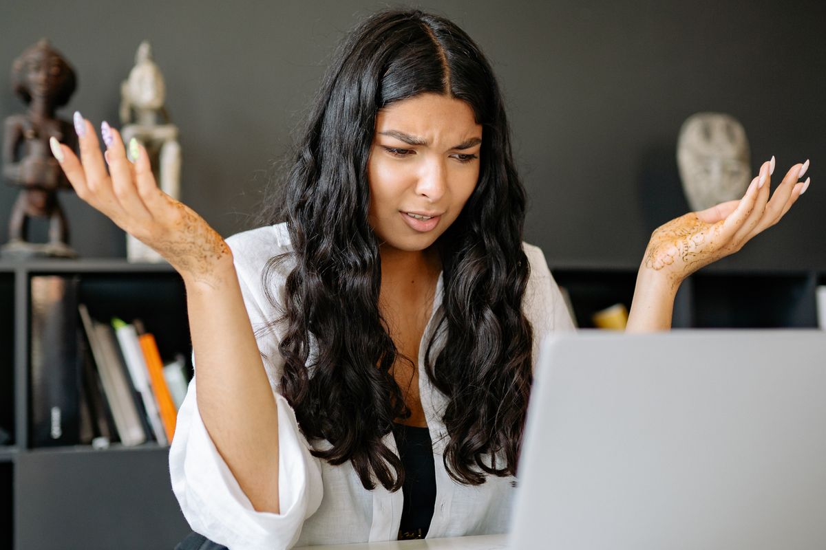 A woman looking confused at her laptop, the same way a patient feels on a slow or confusing medical practice website