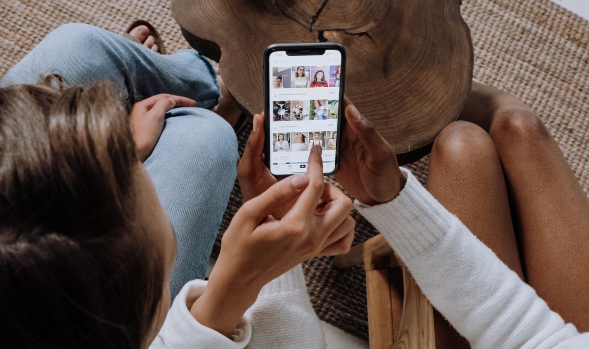 Two people looking at image search results on a phone, representing patients using visual search like Google Lens before booking a doctor