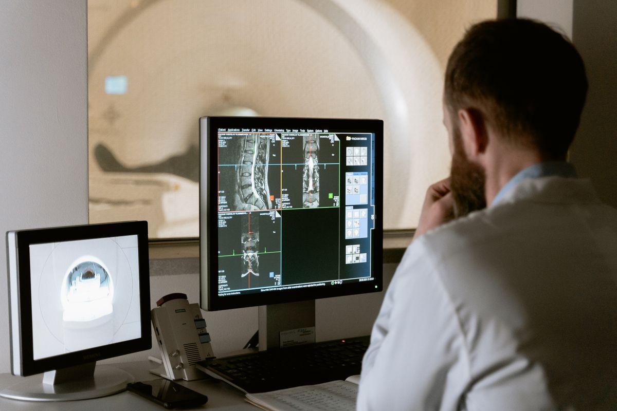 A clinician reviewing scans at a hospital workstation, the kind of AI driven imaging big systems are rolling out