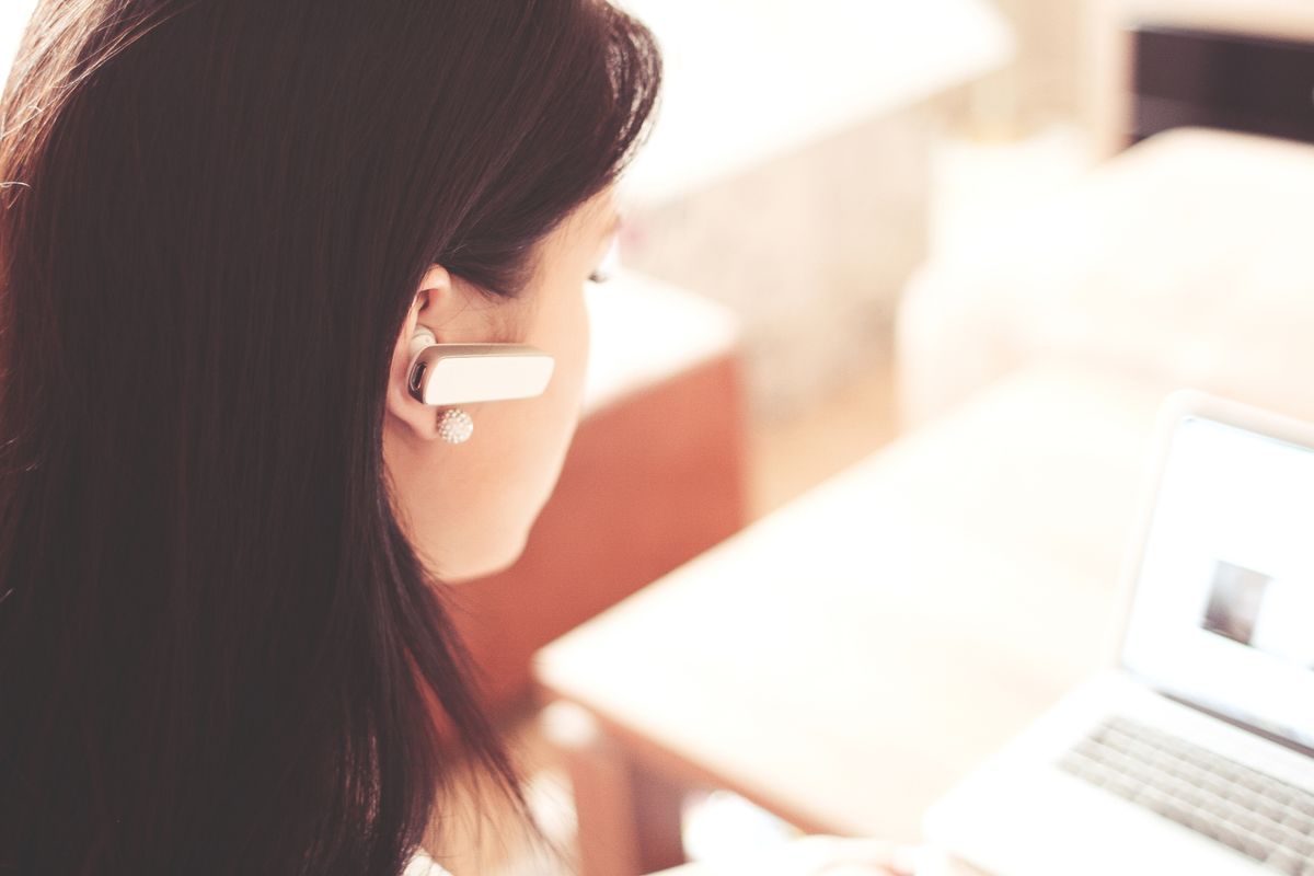 A front desk staffer wearing a headset answering patient calls at a medical practice, illustrating a good call answer rate