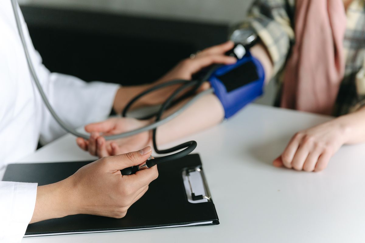 A clinician taking a patient's blood pressure during a routine visit, the kind of recurring appointment that builds patient lifetime value over years